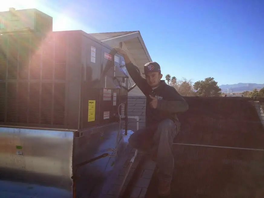 HVAC technician performing Air Duct Repair on a rooftop unit in Monroe